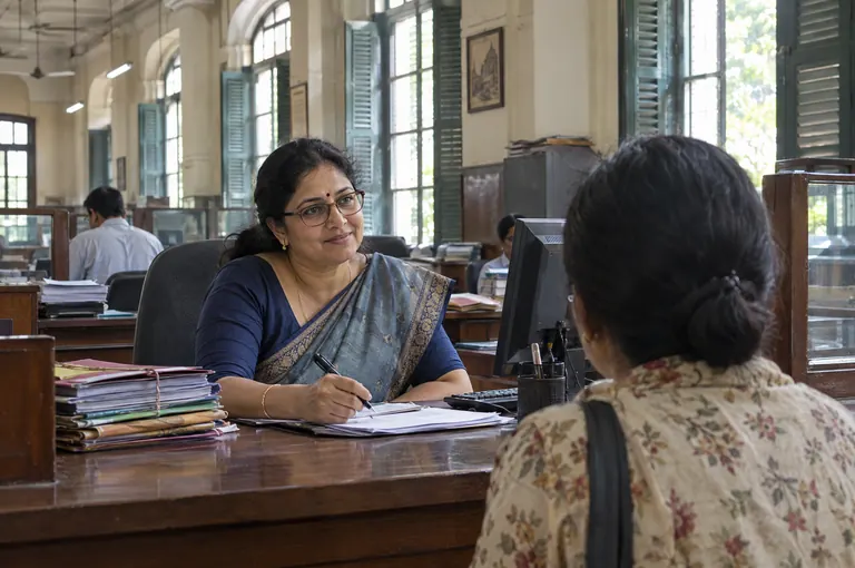 A bank officer in a sari at her desk, helping a customer